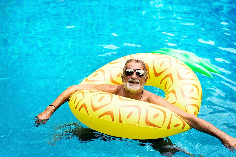 Senior caucasian man floating in the pool with inflatable tube