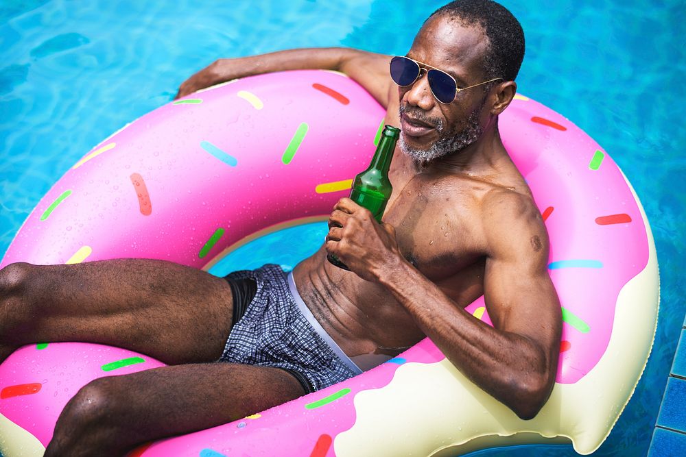 African descent man floating in the swimming pool by inflatable