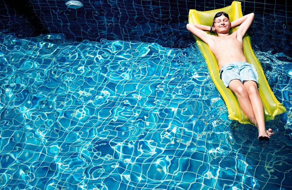 Teenage boy relaxing with pool mattress