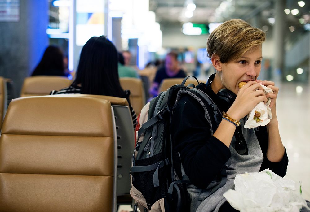 Young caucasian man sitting eating at airport