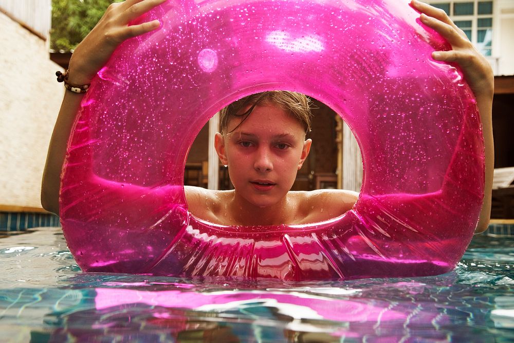 Teenage boy with buoy swimming in the pool