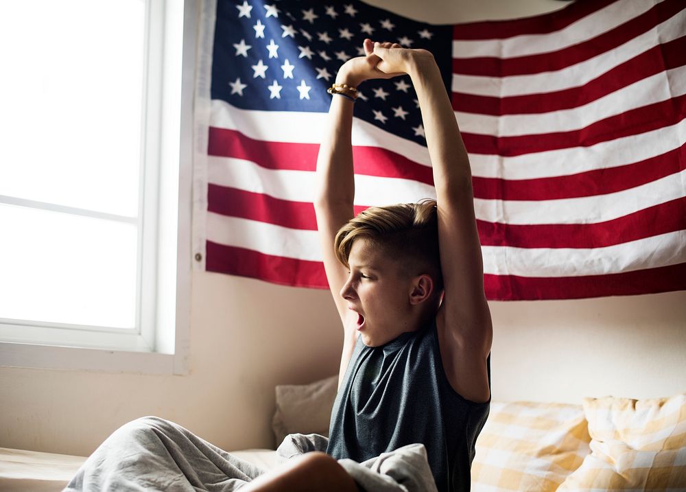 Young caucasian boy waking up stretching arms
