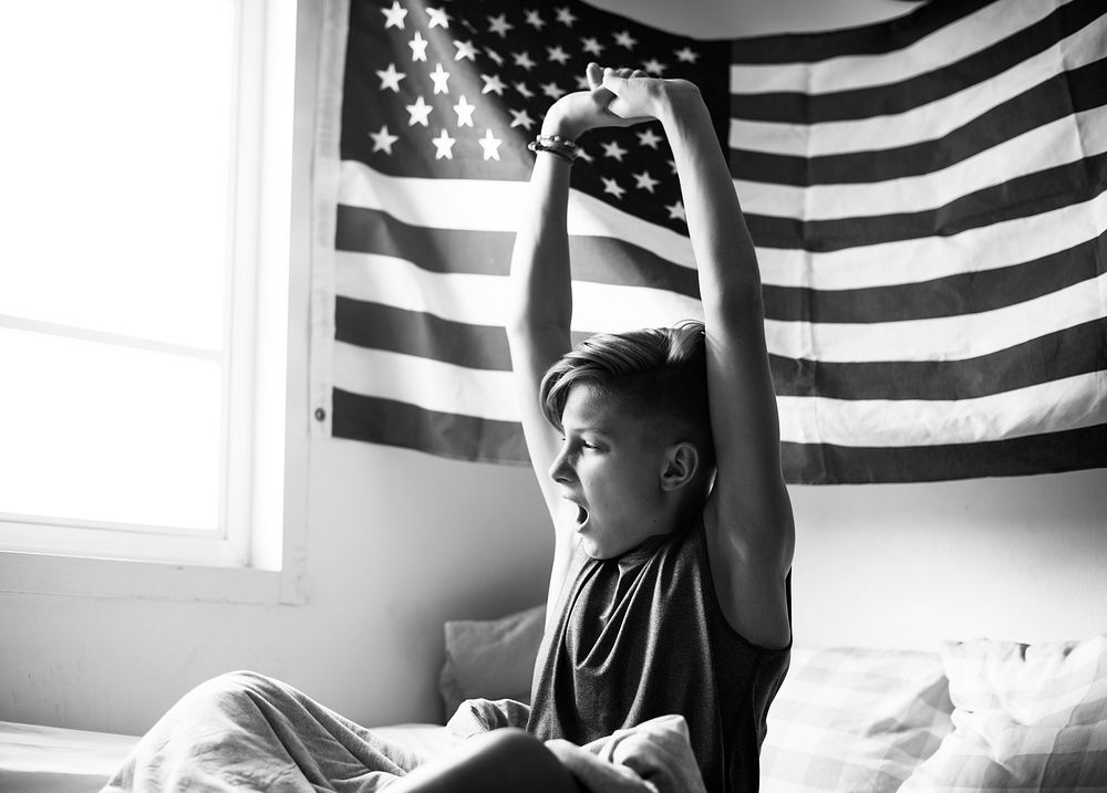 Young caucasian boy waking up stretching arms grayscale