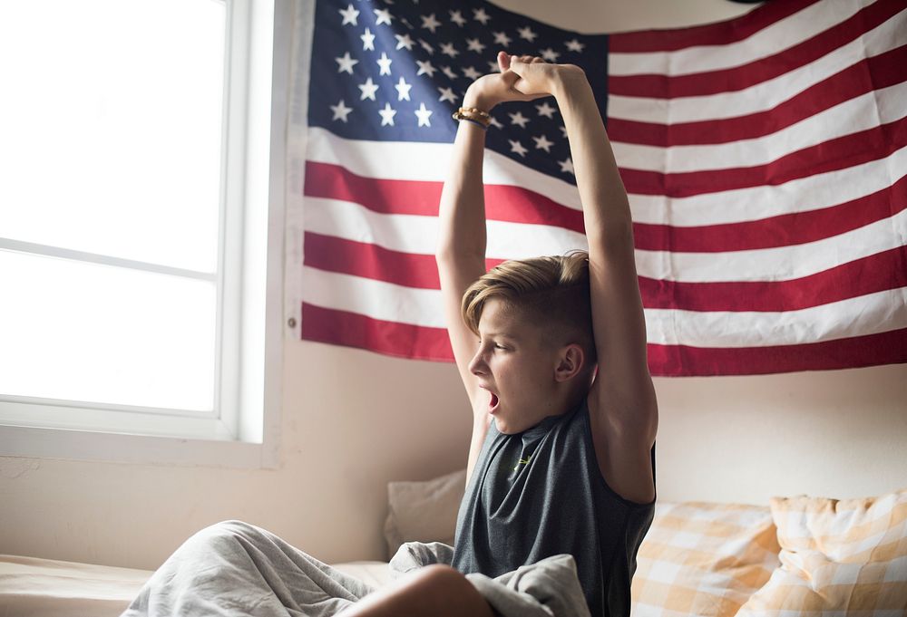 Young caucasian boy waking up stretching arms