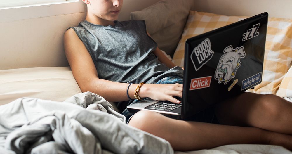 Closeup of young caucasian boy lying using computer laptop on bed