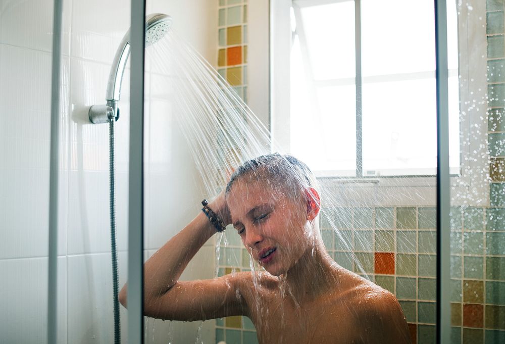 Young caucasian man showering in bathroom