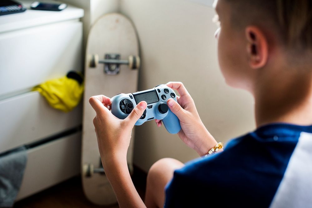 Young caucasian boy holding game control sitting on bed
