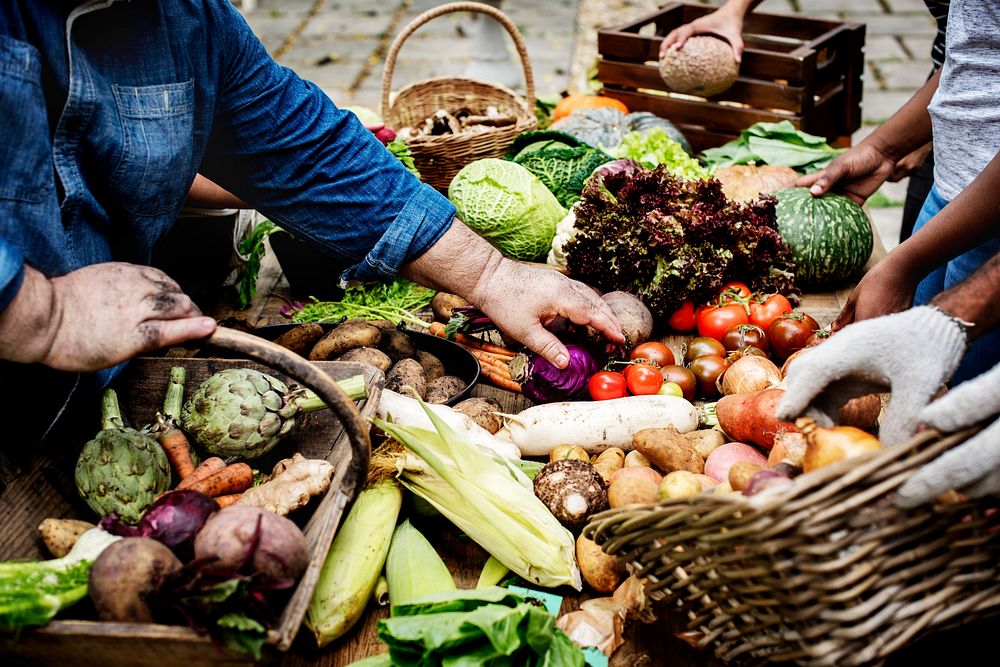 Closeup of hand buying fresh organic vegetable at market