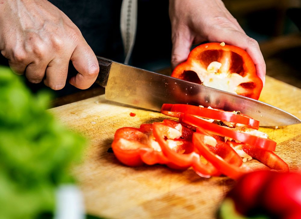 Closeup of hand with knife cutting bell pepper