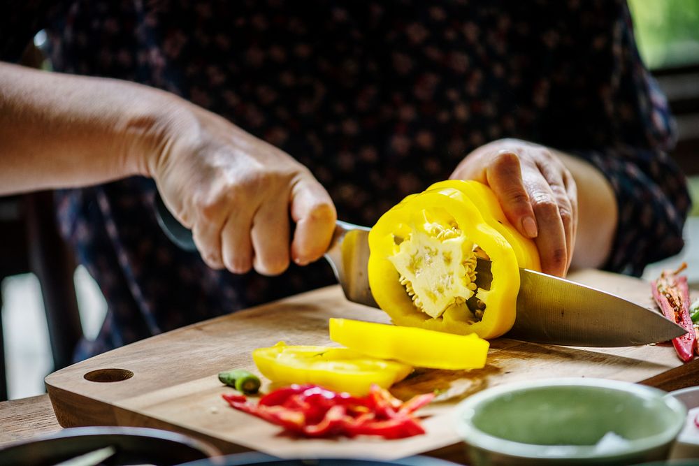 Hands using a knife chopping bell pepper