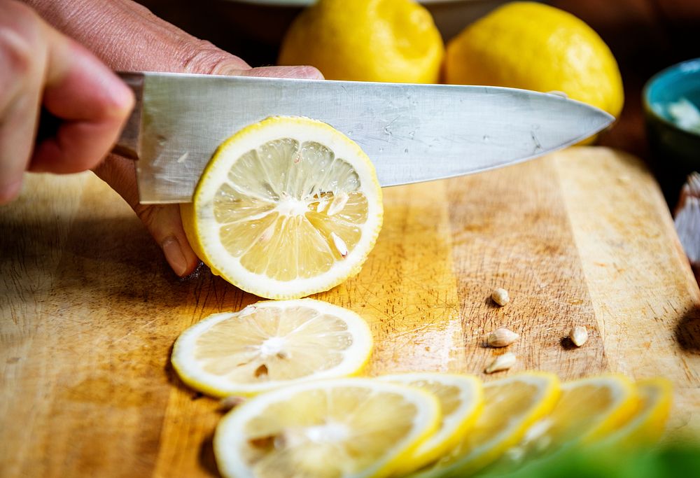 Closeup of hand with knife cutting lemon