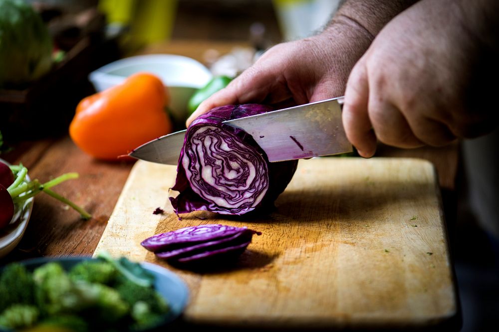 Closeup of hand with knife cutting red cabbage