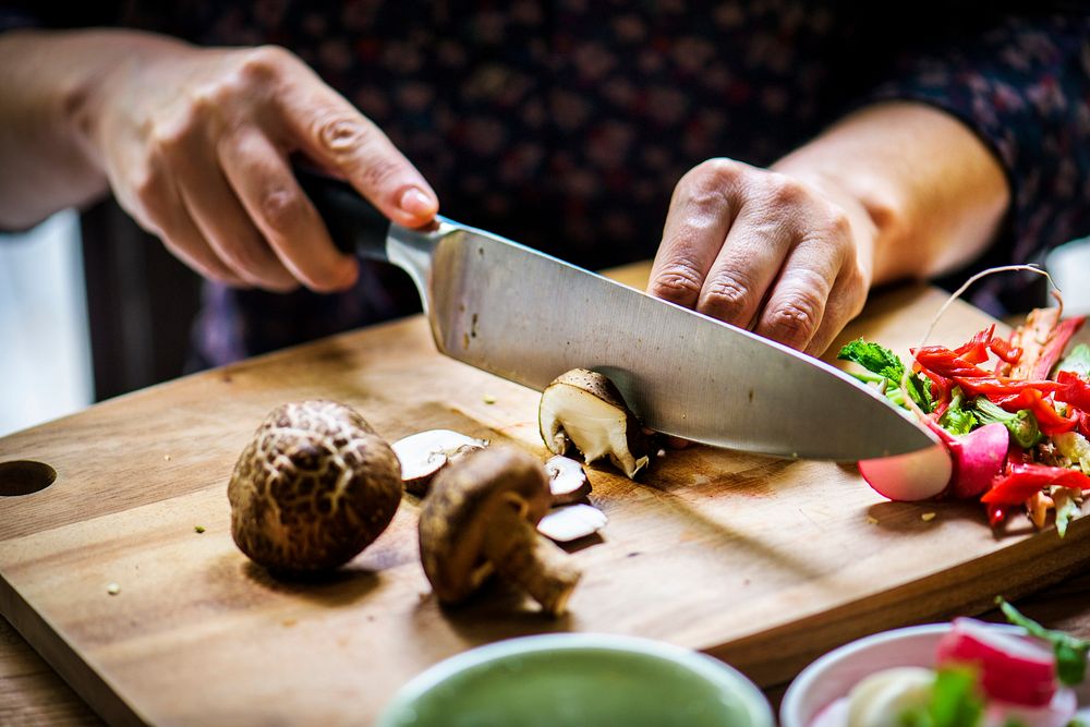 Hands using a knife chopping mushroom