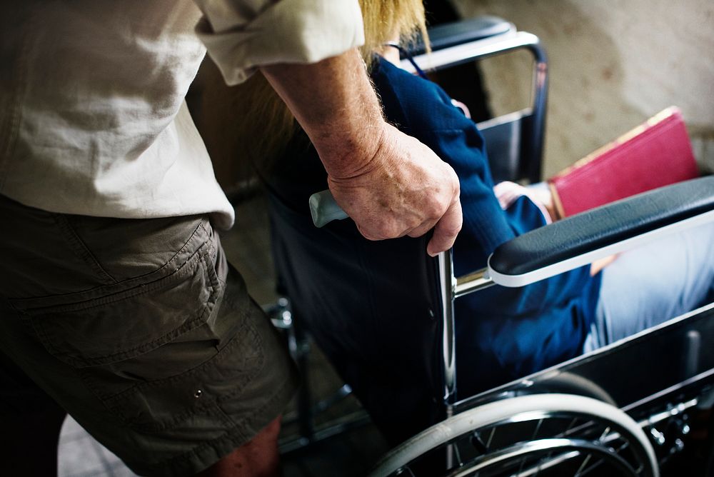 Closeup of senior man pushing the woman wheelchair