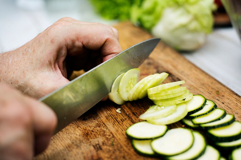 Closeup of hand with knife cutting cucumber