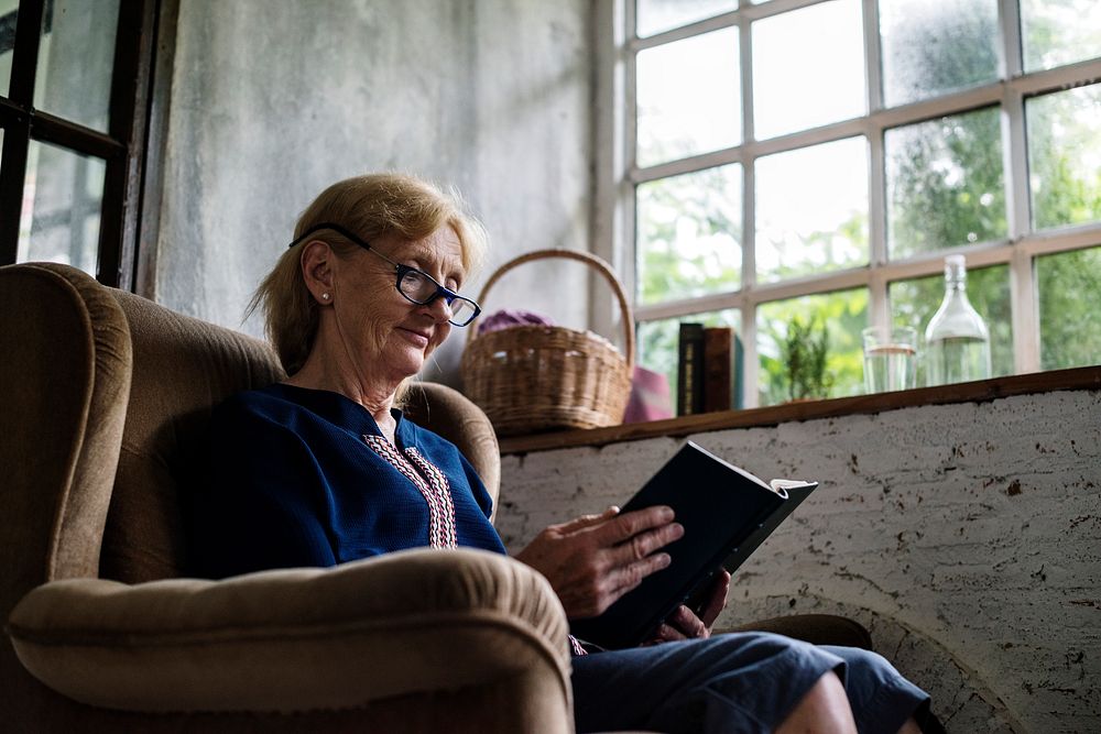 Senior caucasian woman sitting reading book on the couch