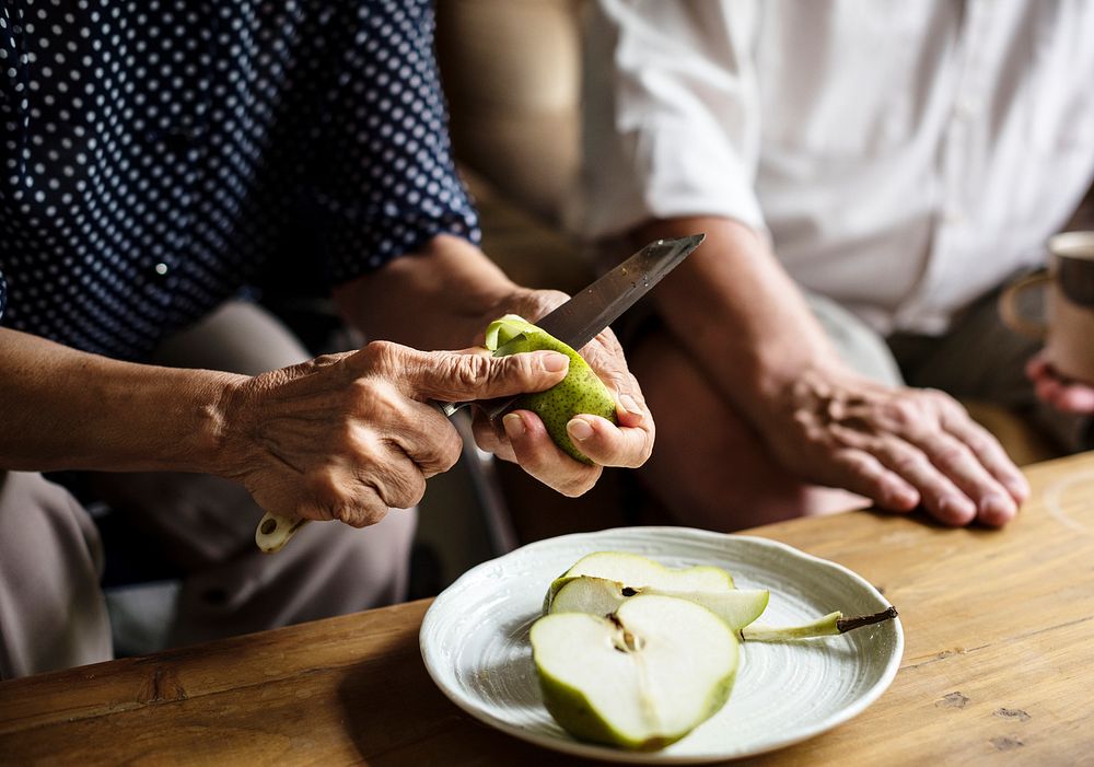 Closeup of hand with knife cutting pear