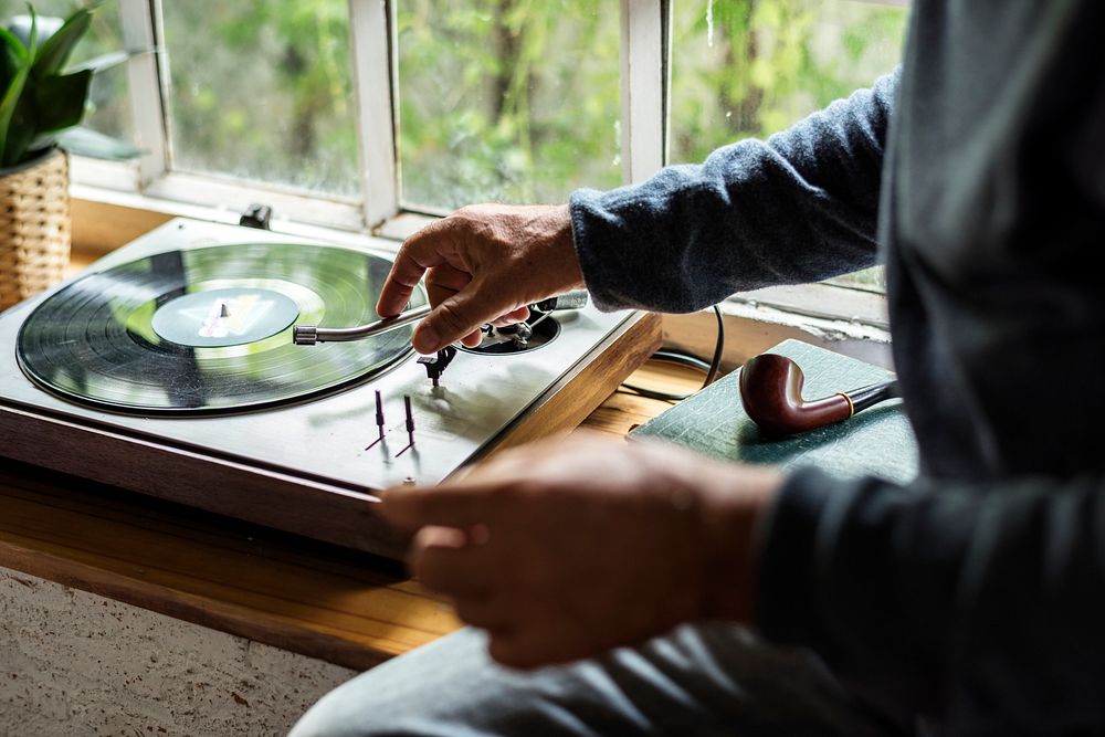 Hands insert vinyl disc to turntable player