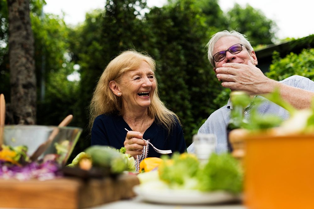 Senior couple eating fresh vegetable salad at backyard together