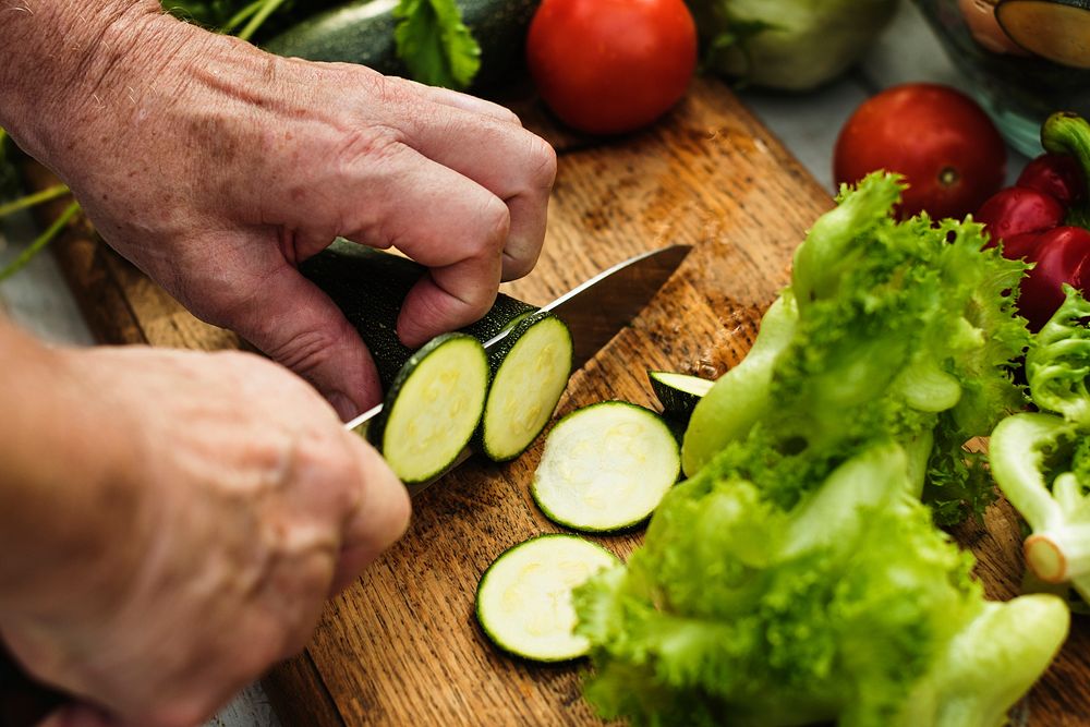 Closeup of hand with knife cutting zucchini