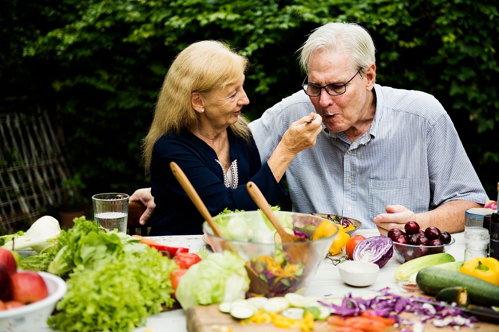 Senior adult couple eating salad outdoor