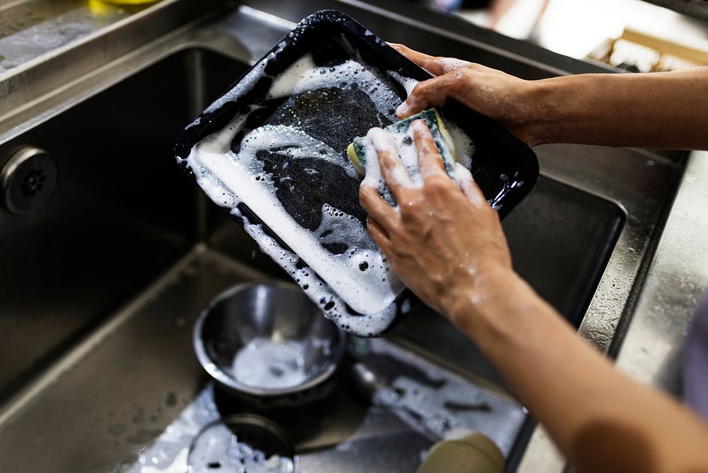 Hands washing kitchenware on the sink