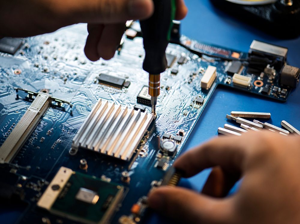 Closeup of hands with screwdriver over computer mainboard