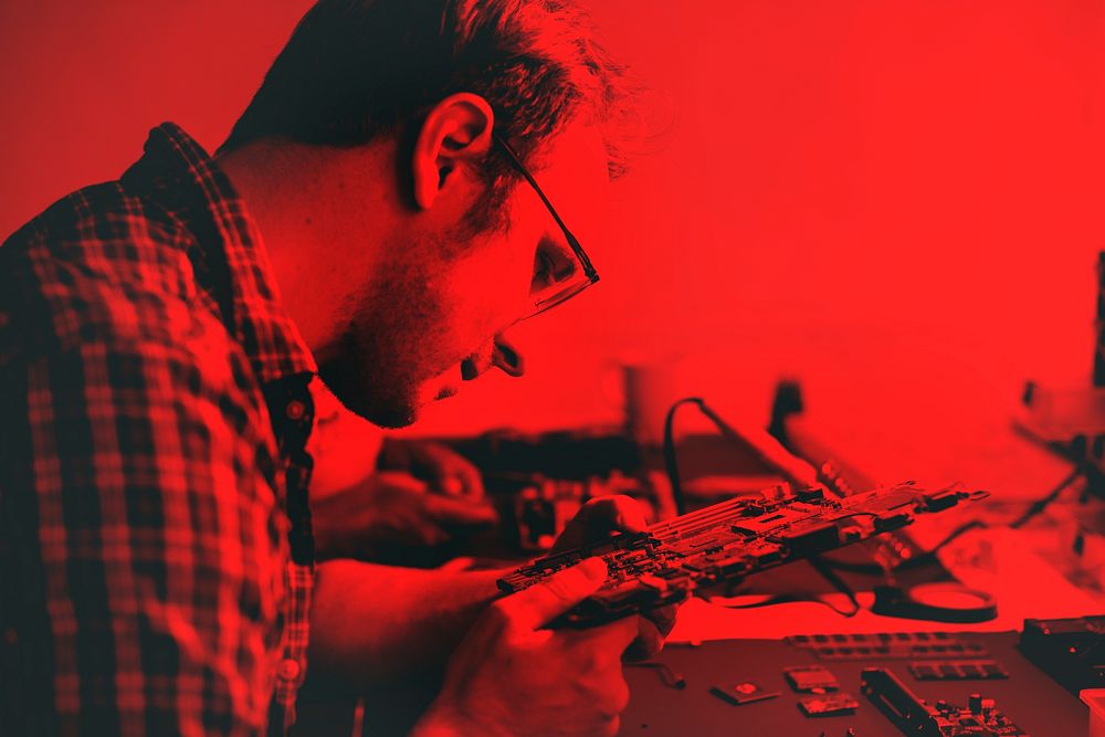 Technicians working on electronics parts red tone