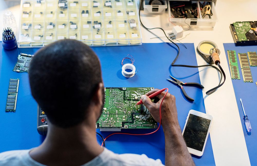 Technician using multimeter with computer electronics parts
