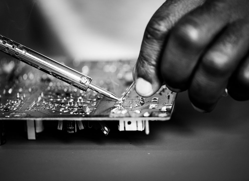 Closeup of hands soldering tin to electronics circuit board