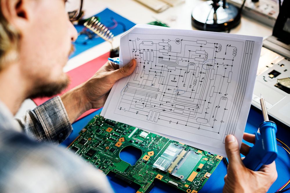Technician studying electronics circuit guideline paper