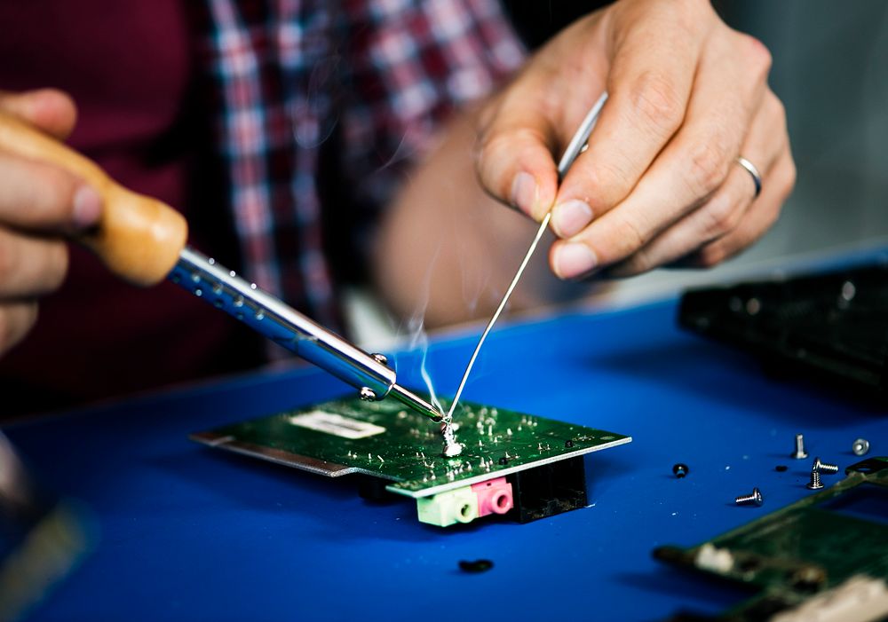 Hands soldering tin on electronics circuit board