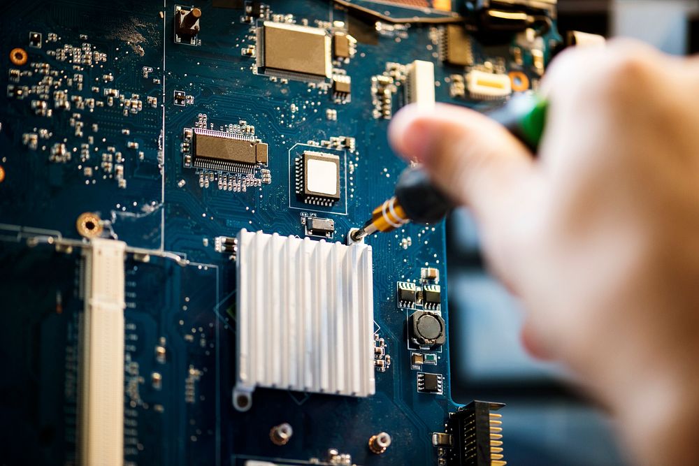 Closeup of hands with screwdriver over computer mainboard