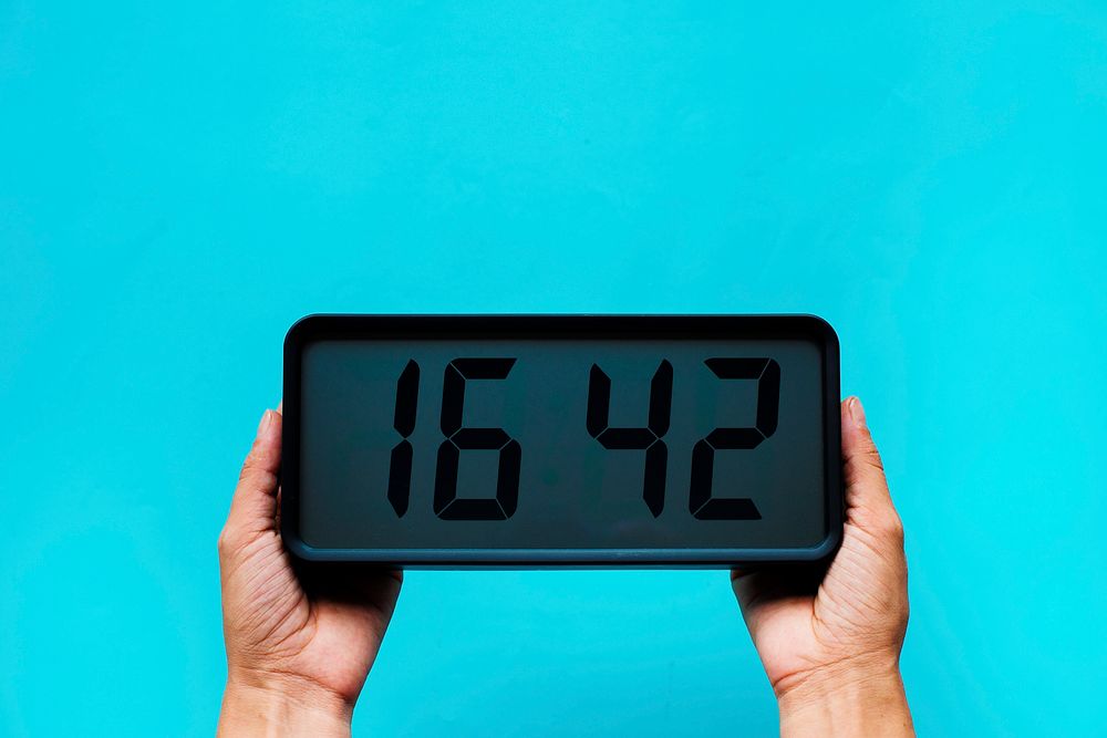 Hands holding digital clock isolated on background