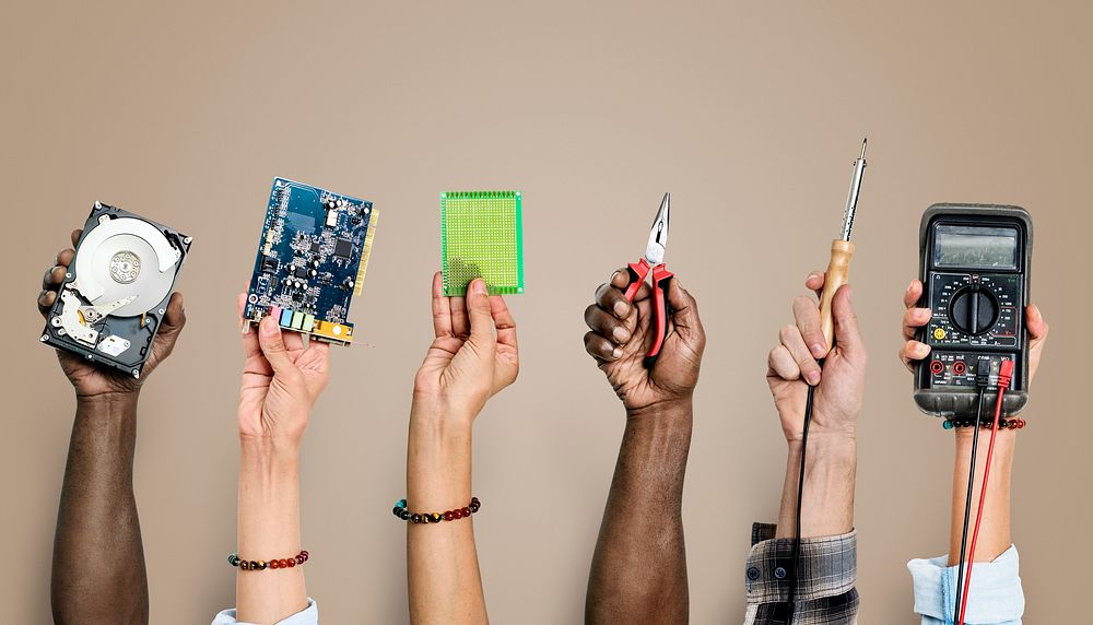 Diverse hands holding electronics tools on brown background