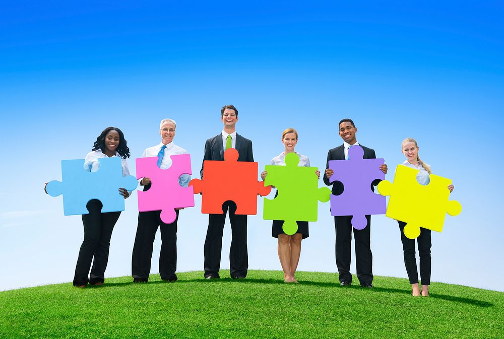 Group of business people holding puzzle pieces.