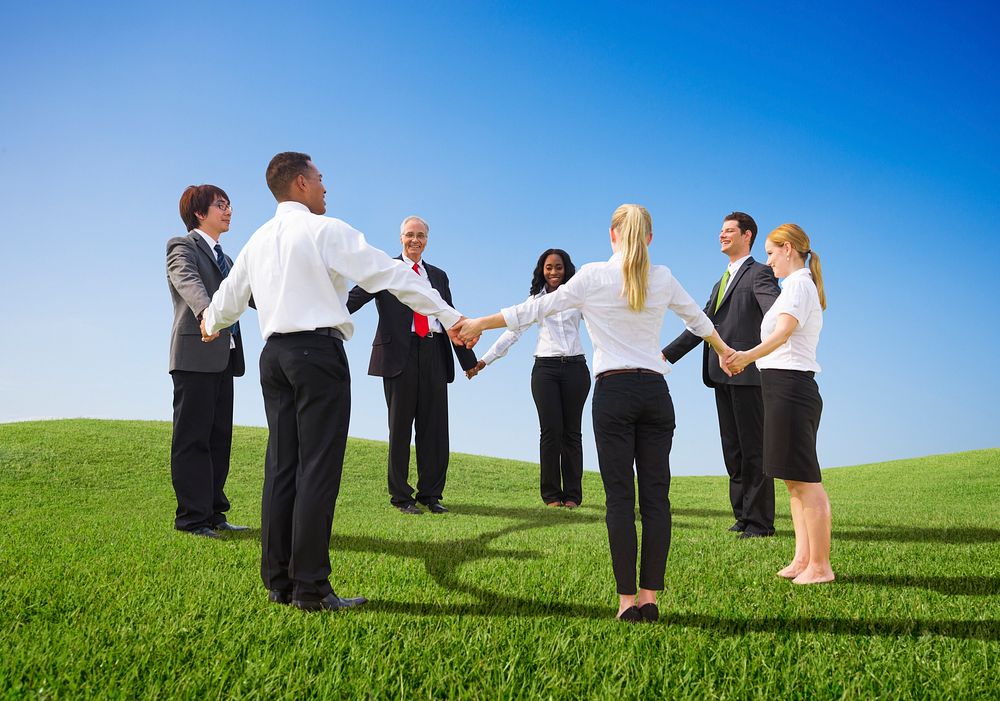 Happy business people outdoors holding hands together