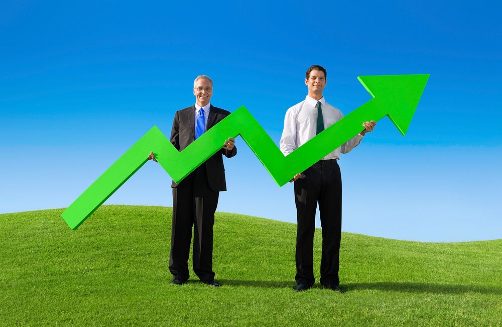 Two Businessmen holding the increase graph on the hill