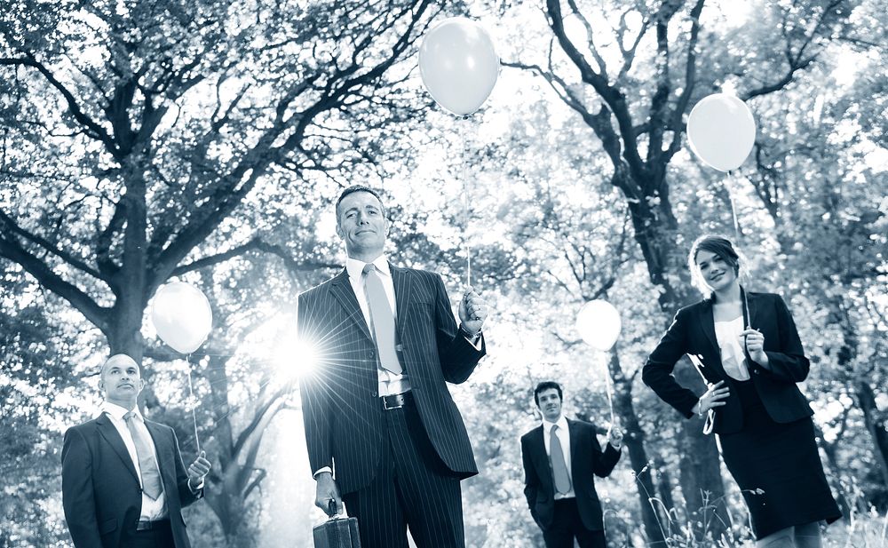 Group of business people holding balloons in the forest