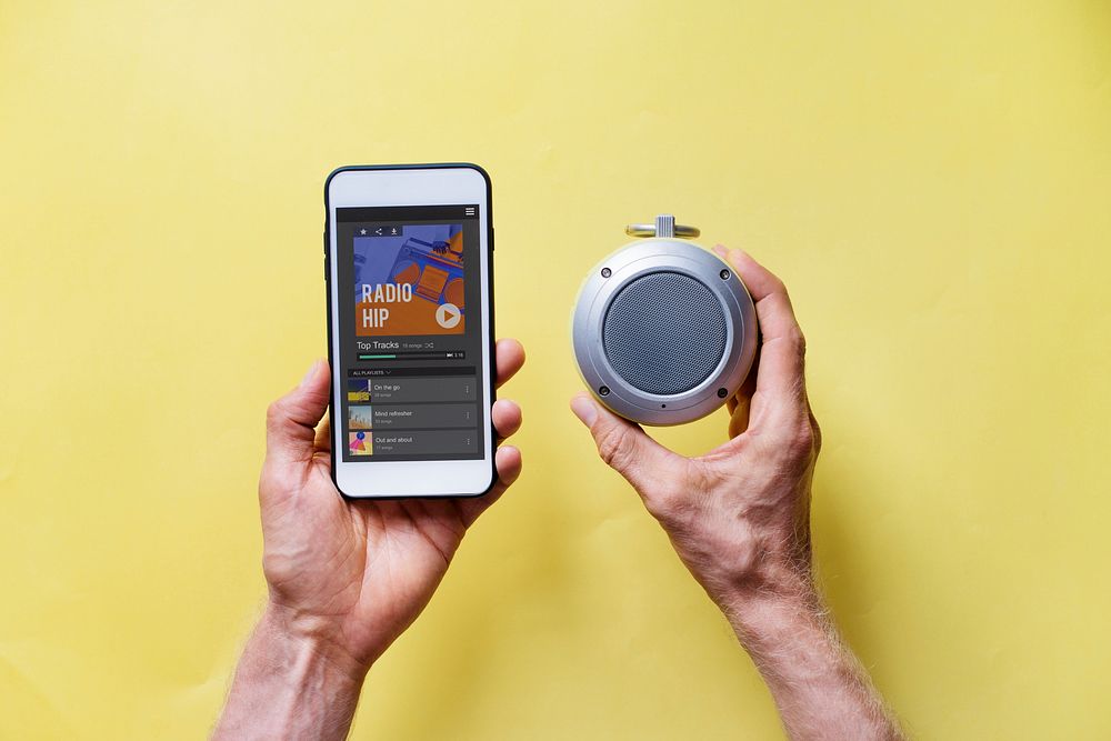 Hands holding smartphone connect to bluetooth speaker