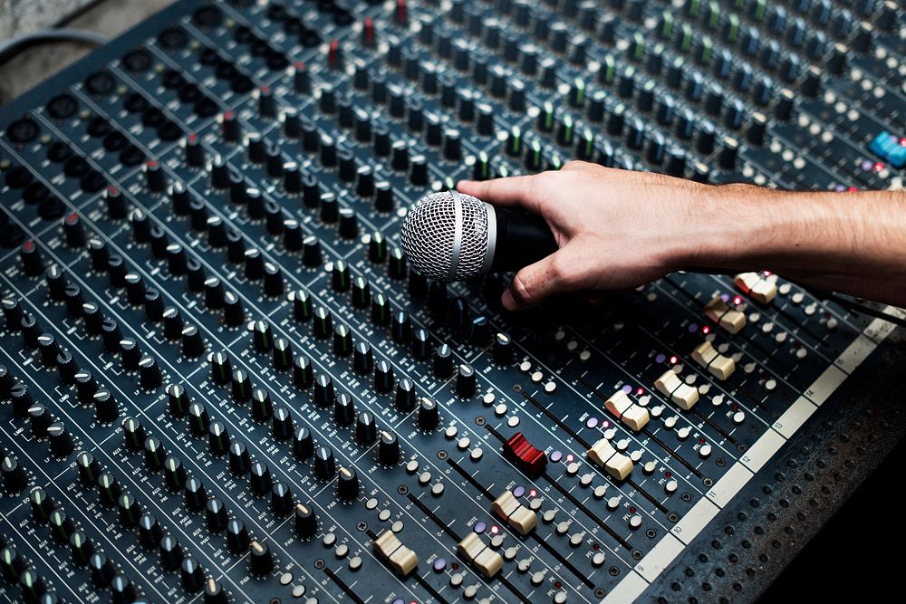 Hand with microphone on a sound mixer