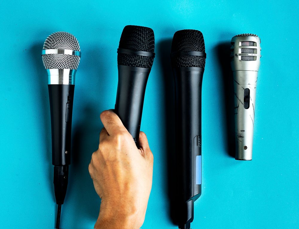 Hand holding microphone isolated on background
