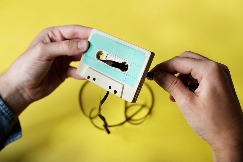 Hands holding a tape cassette rolling back