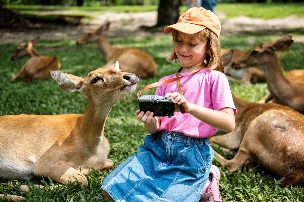 Young caucasian girl taking selfie with deers at the zoo