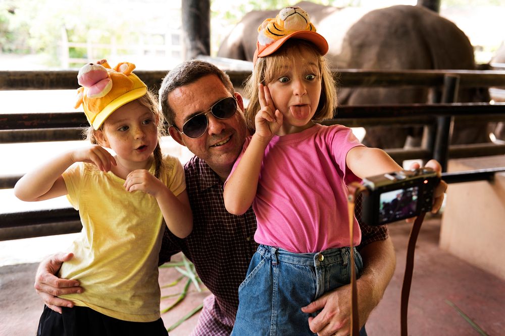 Daughters taking selfie with father at the zoo