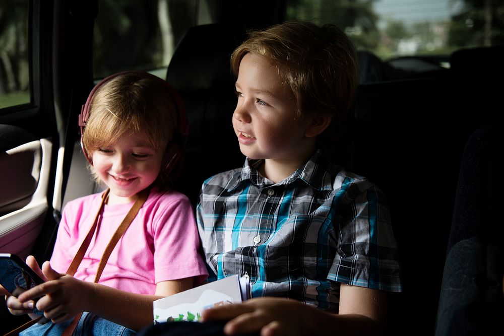 Young caucasian girl sitting inside car with brother