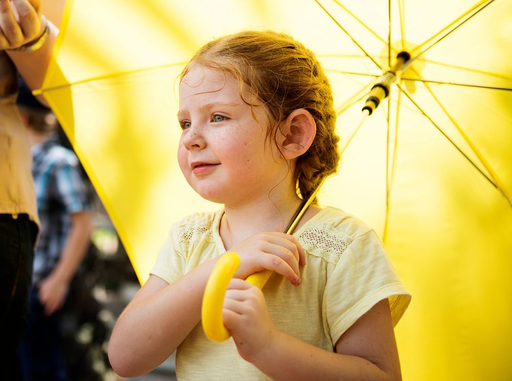 Closeup of young caucasian girl with yellow umbrella
