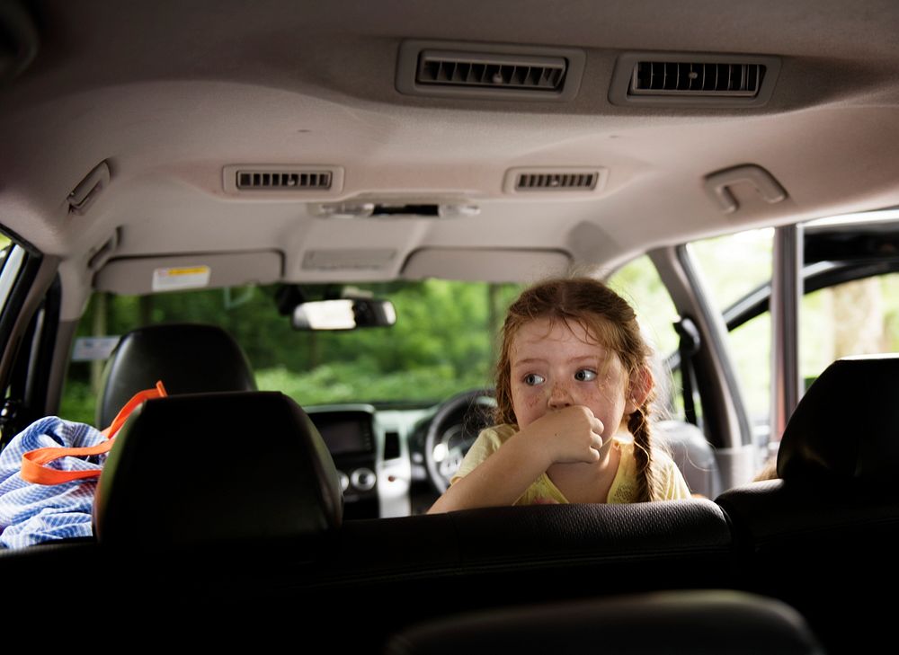 Closeup of young caucasian girl sitting thoughtful inside the car