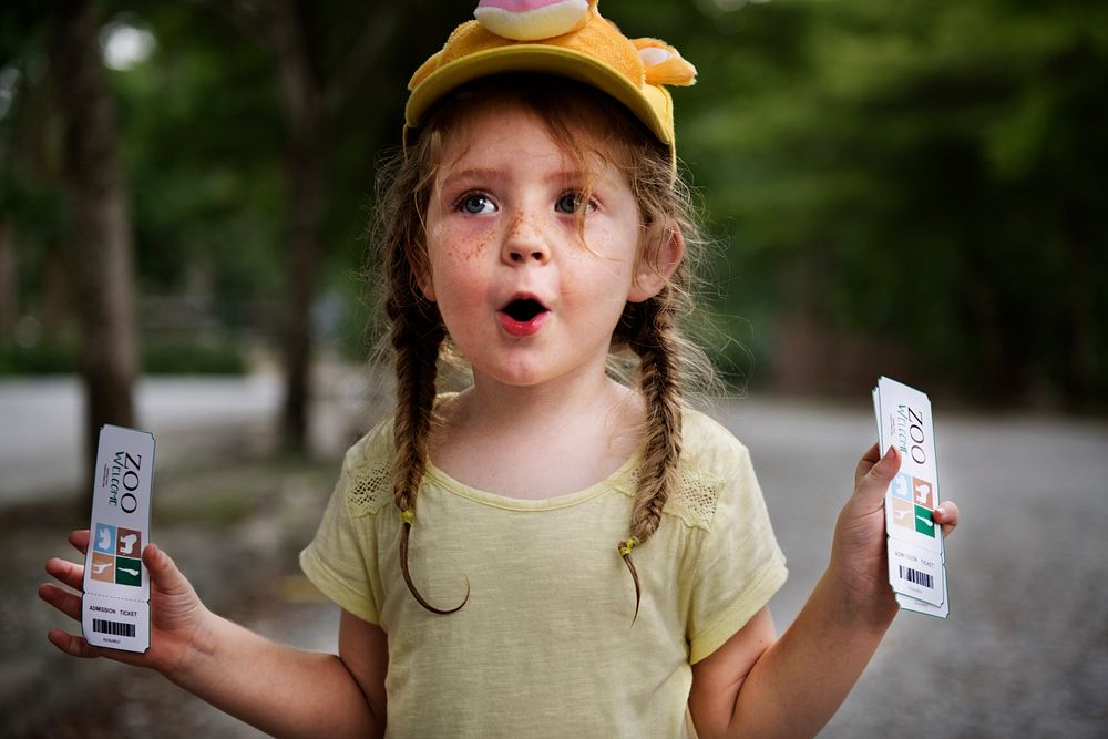 Young caucasian girl with surprise face expression holding zoo ticket
