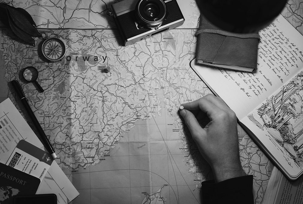 Aerial view of hand pinning on world map journey travel grayscale